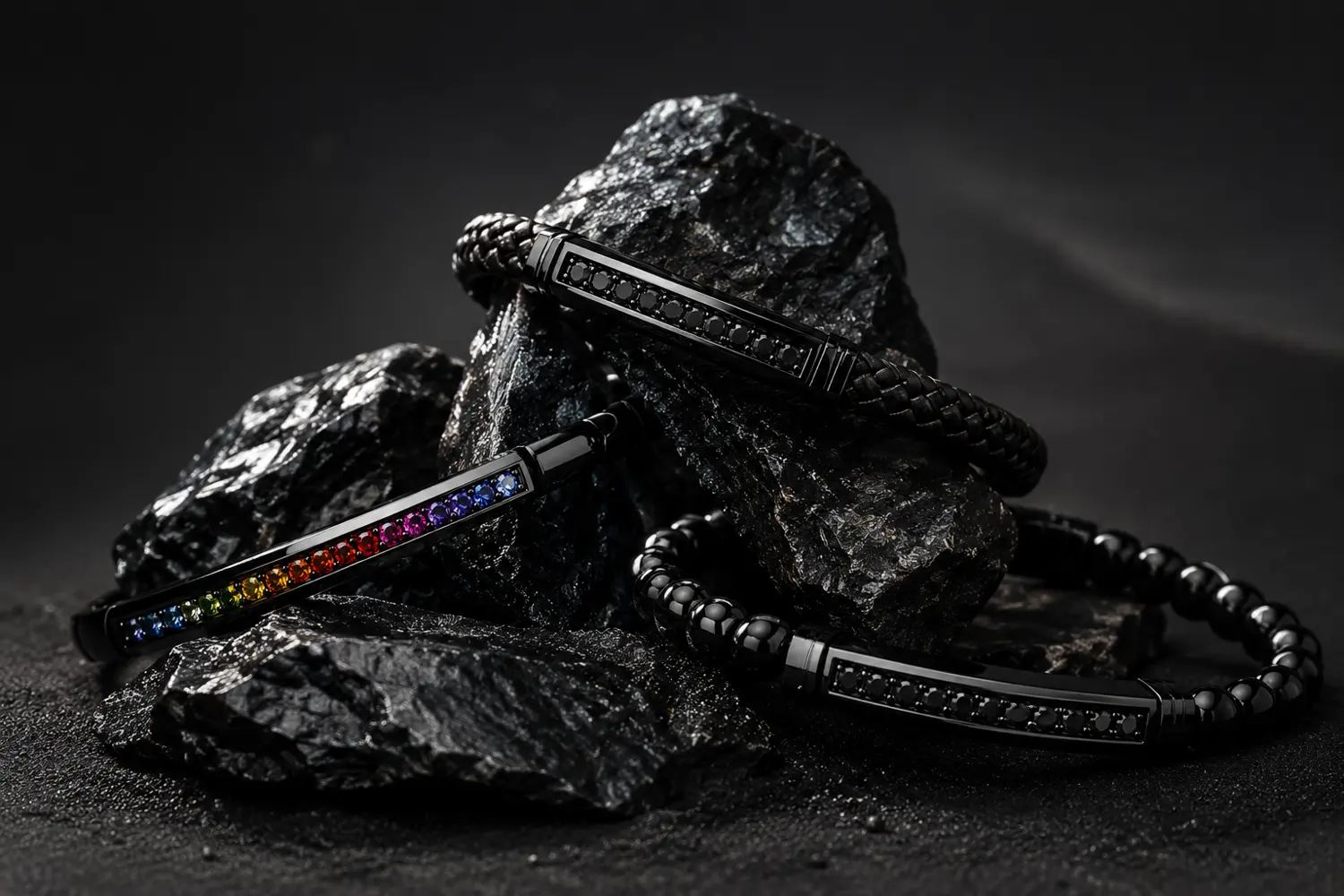 Bracelets Jack Obsidian et Jack Rainbow posés sur des roches d'obsidienne